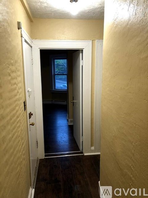 A hallway with a door leading to a dark room.