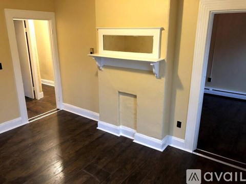 A white shelf is mounted on a wall above a dark hardwood floor.