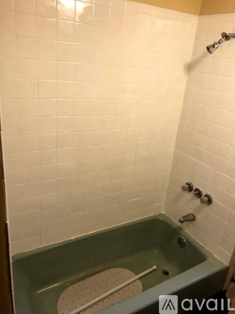 A bathroom with a green tub and white tiles.