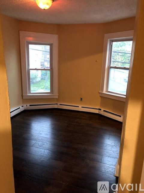 A room with a window and a wooden floor.