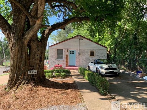 A white car is parked in front of a small house with a blue door.