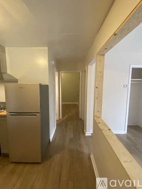 A kitchen with a refrigerator and wooden floors.