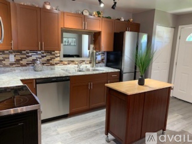 A kitchen with brown cabinets and a marble countertop.