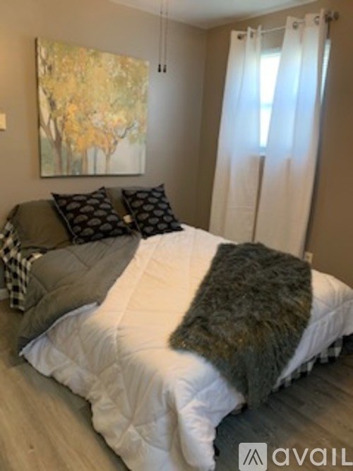 A bed with a white comforter and a grey blanket is in the room.