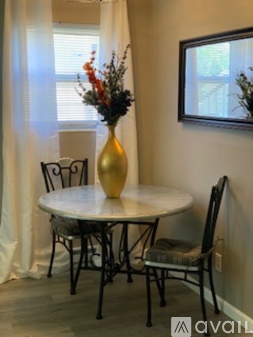 A table with chairs and a vase of flowers in a dining room.