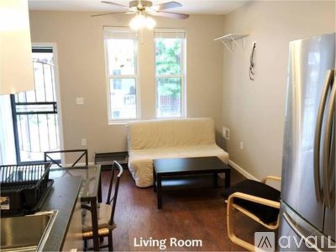 A living room with a couch, chair, and a refrigerator.