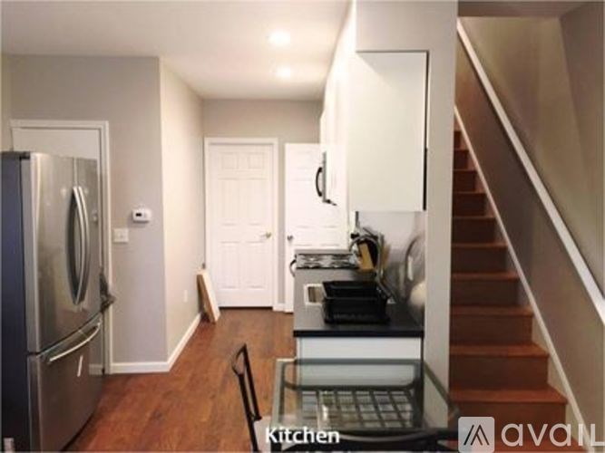 A kitchen with a refrigerator, stove, and a staircase.