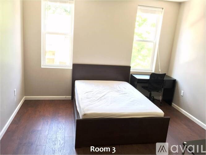 A bedroom with a bed, desk, and window.