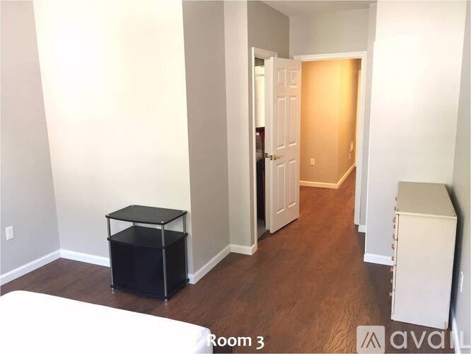 A room with a white bed and a black table in it.