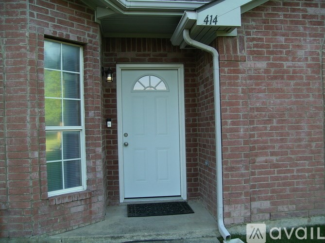 A white door with a window on the left and a brick wall on the right.