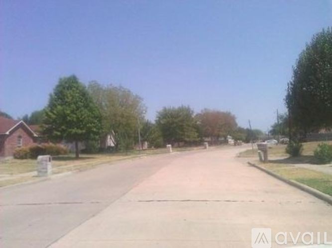 A street with a sidewalk and trees on both sides.