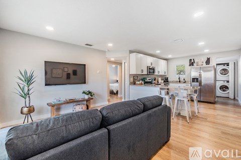 A modern living room with a grey sofa and a kitchen in the background.