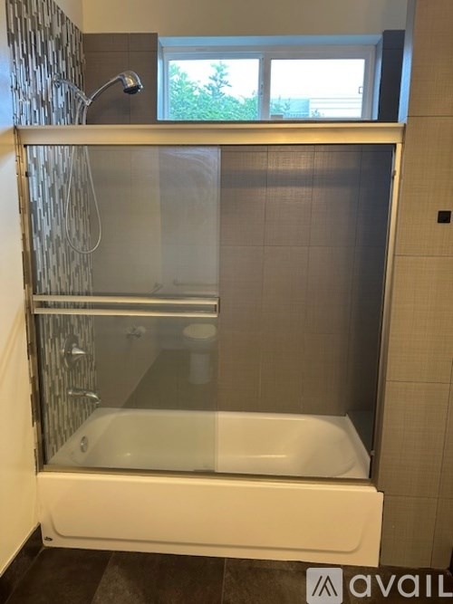 A white bathtub with a glass shower door in a bathroom.