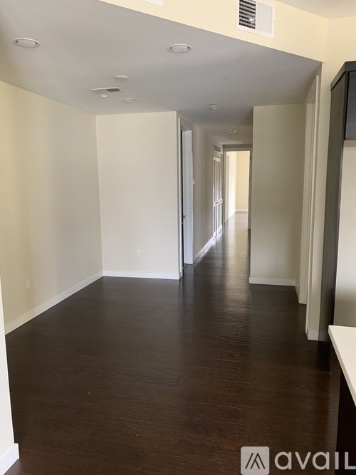 A long hallway with wood floors and white walls.