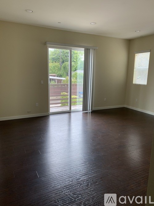 A room with a wooden floor and a sliding glass door leading to a backyard.