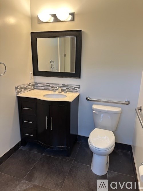 A bathroom with a toilet, sink, and mirror.