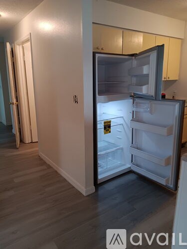 A small, white refrigerator with its door open in a kitchen.
