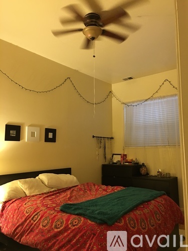A bedroom with a bed, a ceiling fan, and a window with blinds.