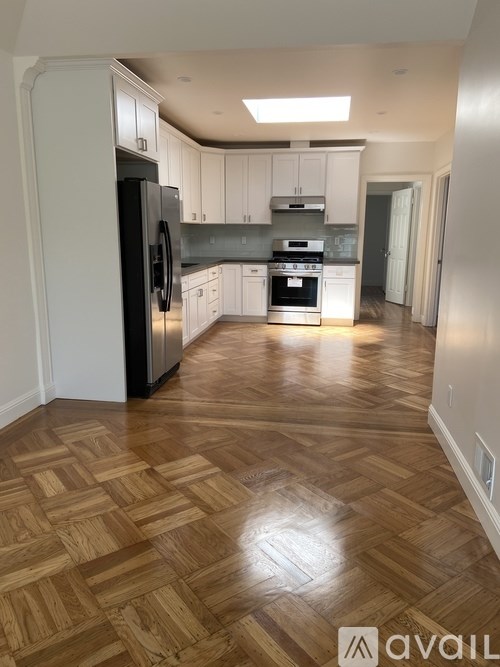 A kitchen with wooden flooring and white cabinets.