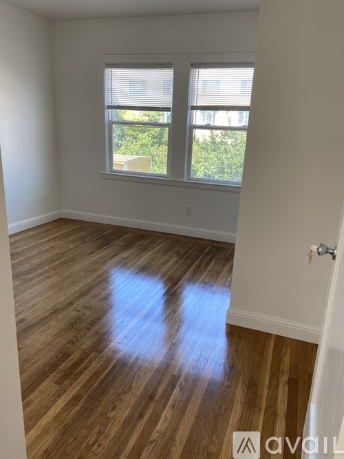 A room with wooden flooring and a window with blinds.