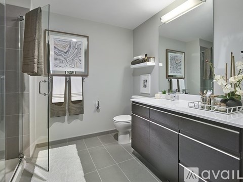 A bathroom with a toilet, sink, and a glass shower stall.