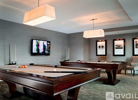 A pool table with a television in the background and a chair to the right.