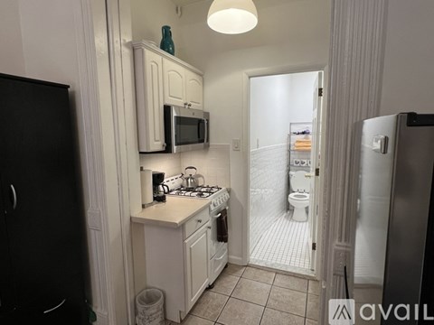 A small kitchen with white cabinets and a black refrigerator.