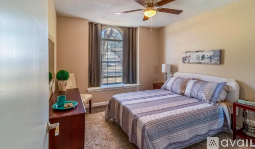 A bedroom with a bed, nightstand, and window.
