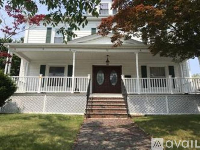 A white house with a red door and a porch.