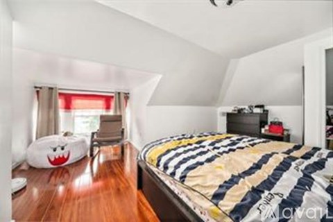 A bedroom with a bed, a chair, and a pillow with a face on it.