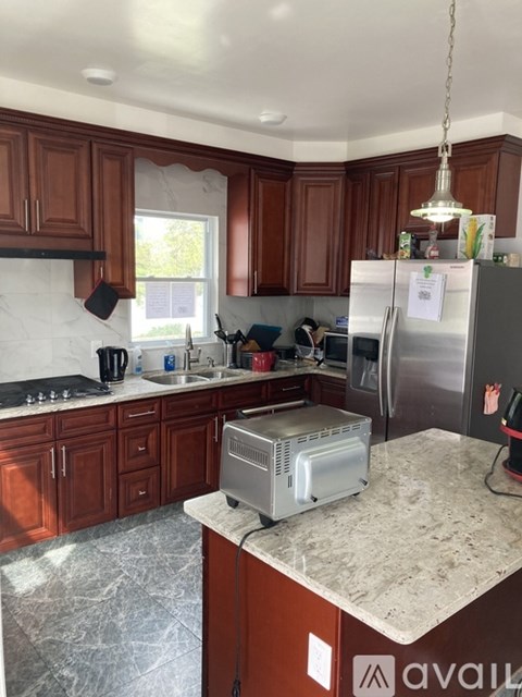 A kitchen with brown cabinets and a marble countertop.