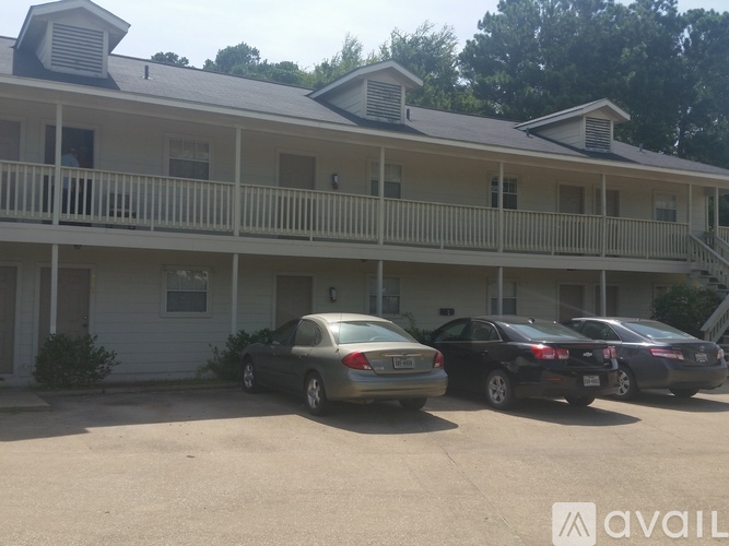 Two cars are parked in front of a two-story building.