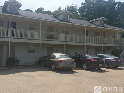 Two cars are parked in front of a two-story building.