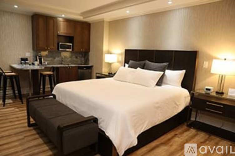 A bedroom with a large bed and a kitchenette area.