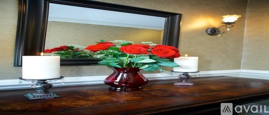A vase with red flowers sits on a table next to two candles.