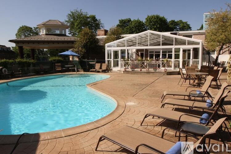 A pool with a glass enclosure and lounge chairs.