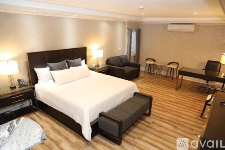 A well-lit bedroom with a large bed and a seating area.