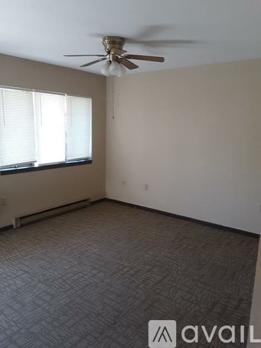 A room with a ceiling fan and carpeted floor.