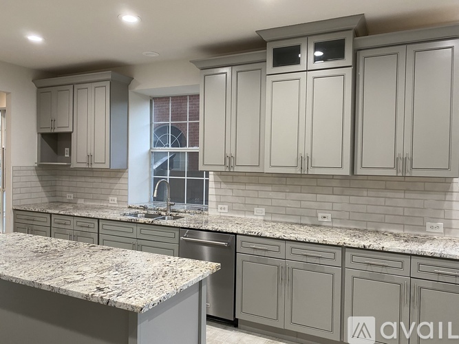 A kitchen with granite countertops and grey cabinets.