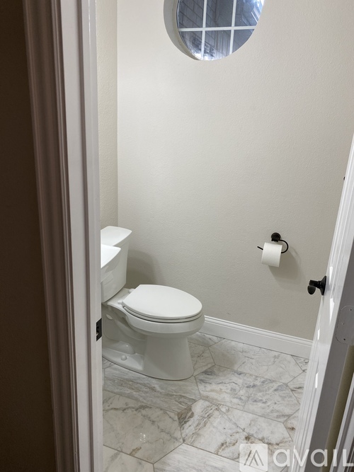 A white toilet in a bathroom with a marble floor.