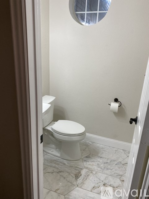 A white toilet in a bathroom with a marble floor.