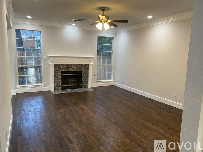 A spacious room with a fireplace and wood flooring.