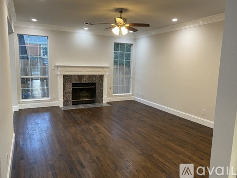 A spacious room with a fireplace and wood flooring.