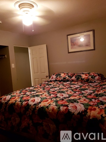 A bedroom with a floral bedspread and a picture on the wall.