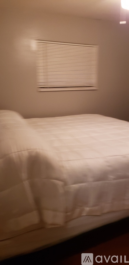 A white bed with a white pillow and a white blanket.