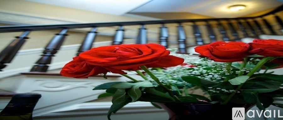 Three red roses in a vase on a table.