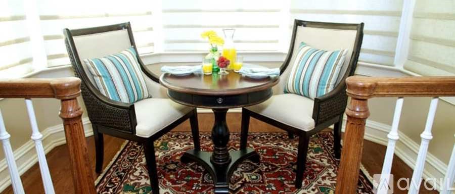 A table with two chairs and a vase of flowers on it.