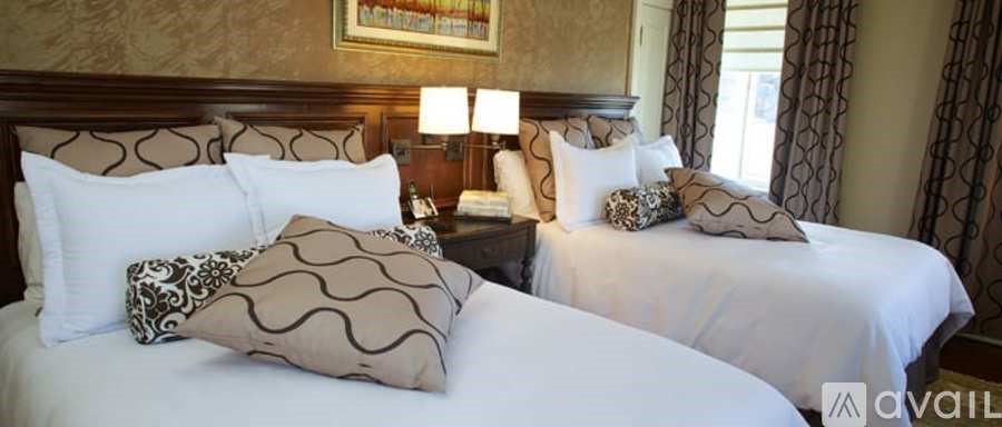 Two beds with white bedding and patterned pillows in a room.
