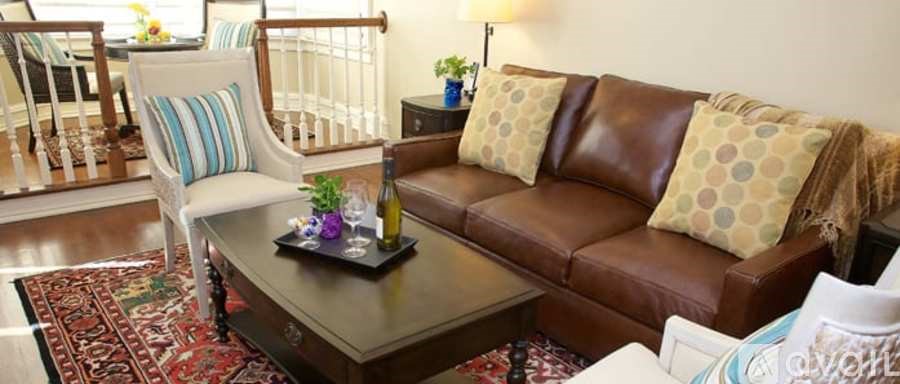 A living room with a brown leather couch and a white chair.