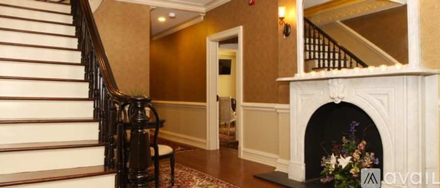 A staircase with a black railing and a white handrail leads to a landing with a fireplace.